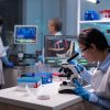 Biochemist scientists studying reaction of virus on microscope in laboratory